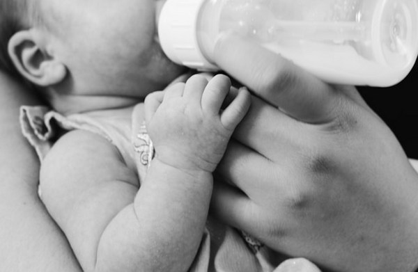 a baby bottle being fed by a hand