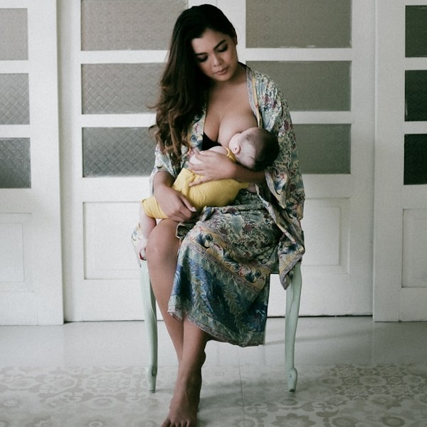 a woman sitting in a chair holding a baby