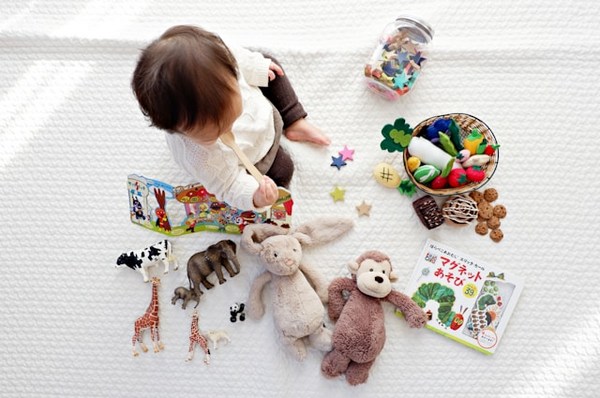 a baby sitting on a white blanket with toys