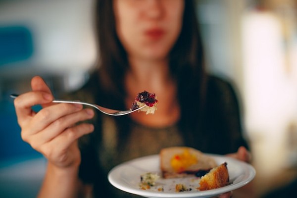 a woman holding a fork and a plate of food