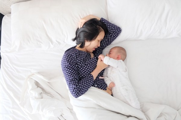 a woman lying in bed with a baby