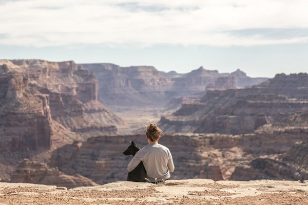 a woman sitting on a rock with a dog