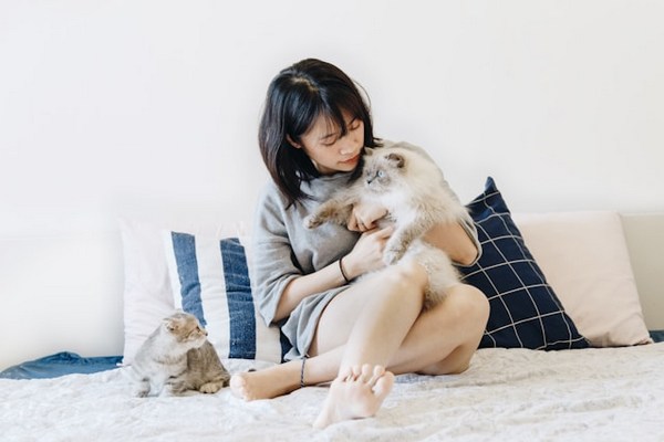 a woman sitting on a bed with a cat