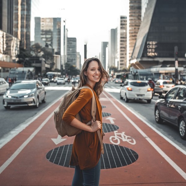 a woman standing on a street with cars and buildings in the background